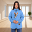 Person wearing a blue sweatshirt with a cat, standing indoors.
