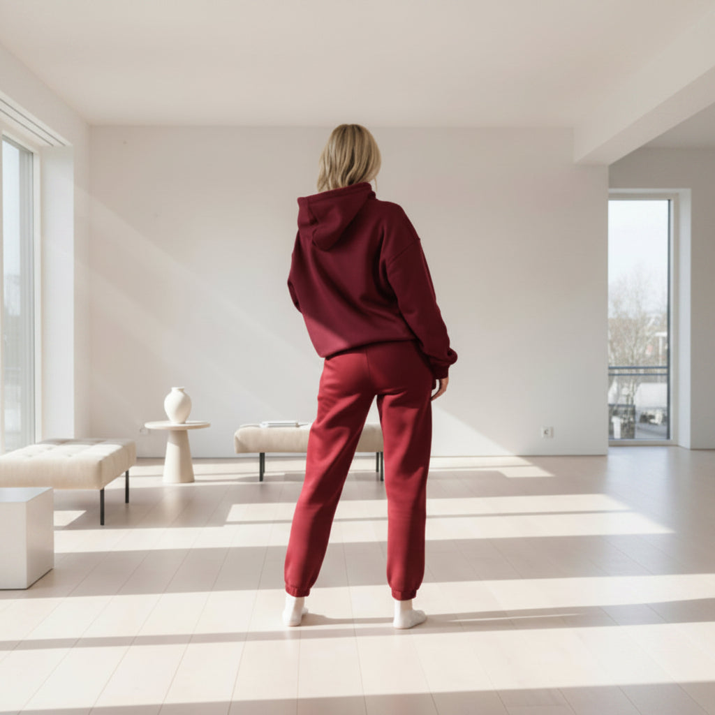 Person wearing a  Burgundy hoodie and pants on a light background
