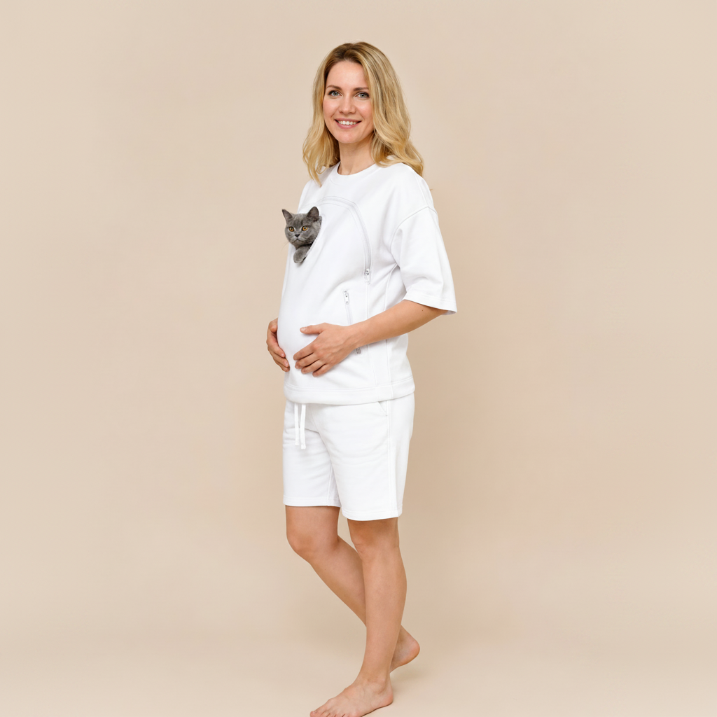 Woman wearing a white t-shirt with a cat sweatshirt and shorts, standing against a beige background