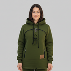 A woman wearing an dark green hooded sweatshirt with black drawstrings and a circular graphic print on the chest, standing against a solid gray studio background.