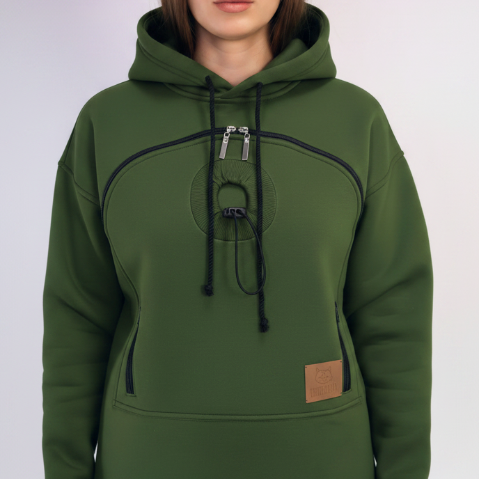 An dark green pullover hoodie with a unique circular chest design, black drawstrings, and a small brown leather patch on the front pocket, shown on a model.