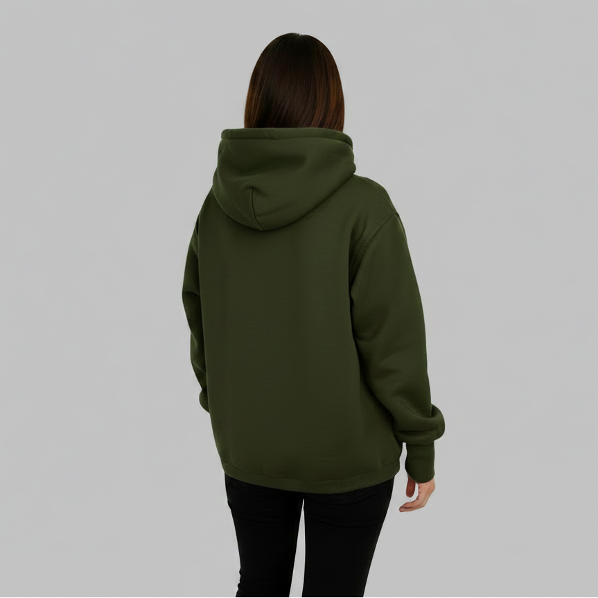 A person viewed from behind wearing an dark green pullover hoodie and black pants, standing in a bright, modern minimalist room with large windows and natural light.
