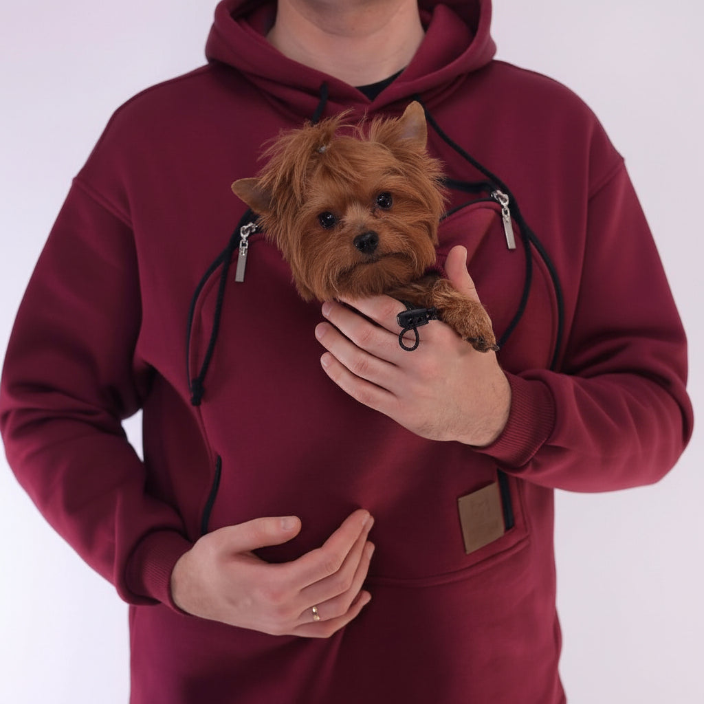Person wearing a Red Burgundy hoodie with a pocket holding a small dog