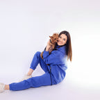 Woman in a Royal Blue tracksuit holding a small dog on a white background