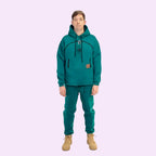 Person wearing a teal hoodie and pants with beige boots on a white background