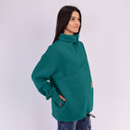 Woman wearing a teal sweatshirt on a white background