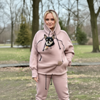 Person wearing a beige hoodie with a dog, standing outdoors.