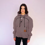 Person wearing a beige hoodie with black accents on a white background
