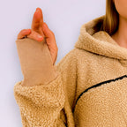 Close-up of a person wearing a beige boucle fleece jacket with a plain background