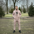 Man wearing a beige hoodie and pants with a dog.