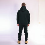 Person wearing a black hoodie and pants on a white background