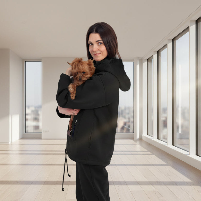 Woman in black tracksuit holding a small dog in a white room with plants.