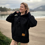 Woman wearing a black boucle  fleece pullover with a hood by a lake.