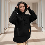 Person wearing a black boucle fleece hoodie in a room with light-colored floor and walls.