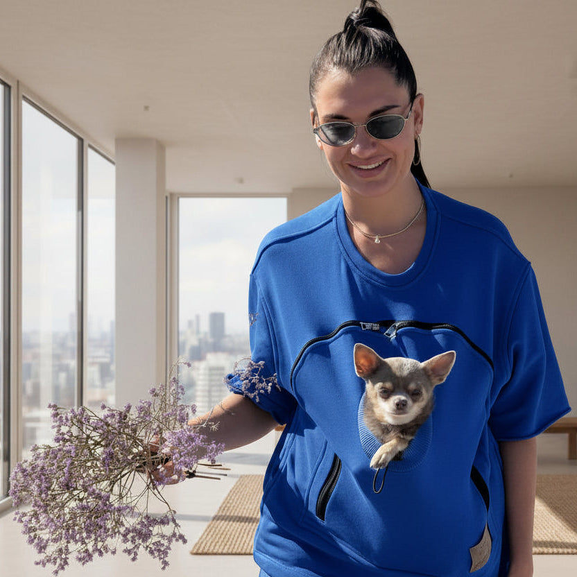 Person wearing a blue t-shirt with a dog in the pouch, holding flowers. Main image