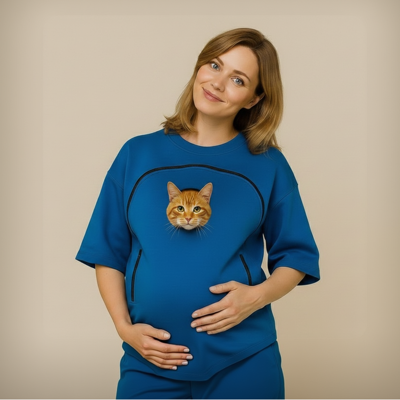 Woman wearing a blue shirt with a cat inside on a beige background Main image