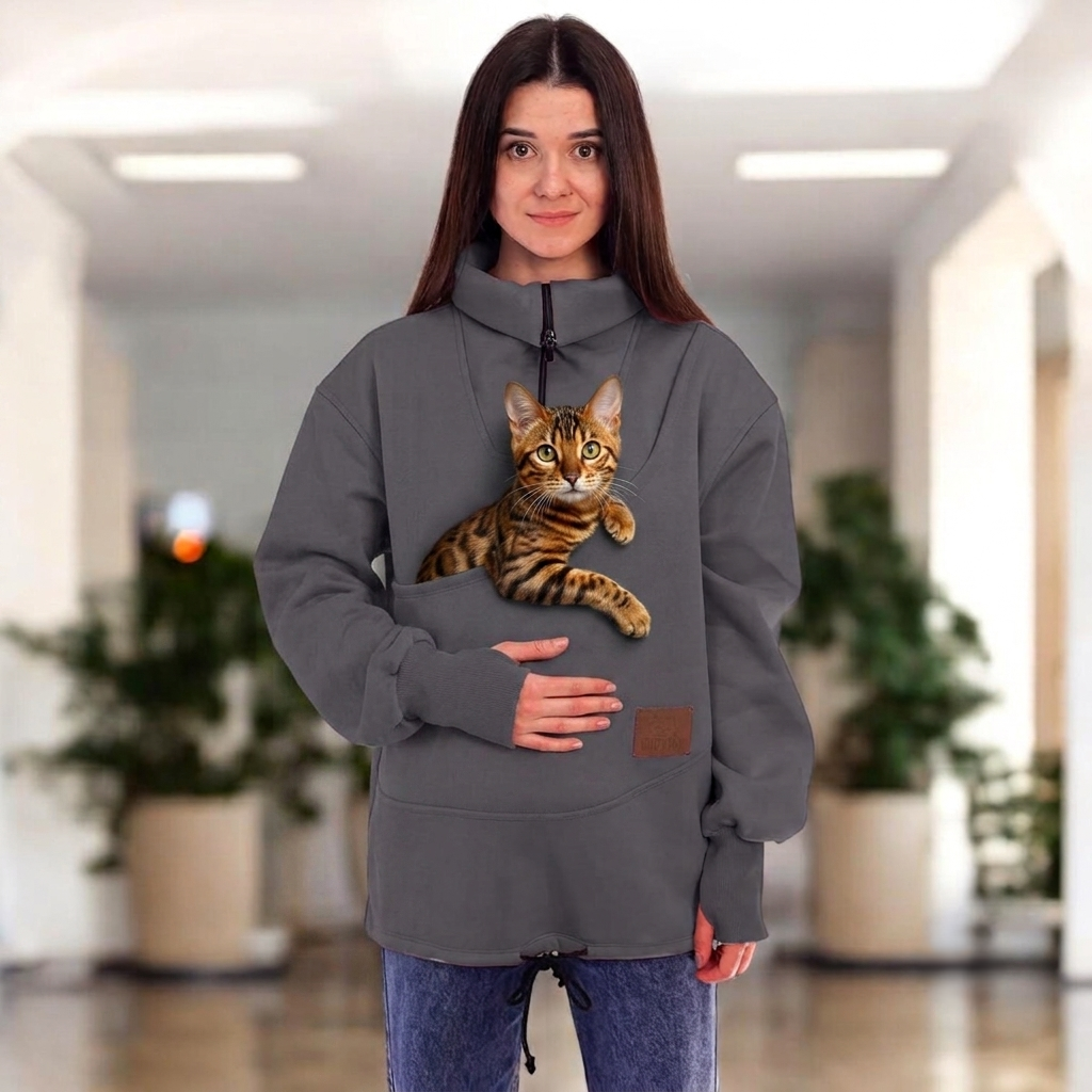 Women wearing a gray sweatshirt with a cat in the pocket on a blurred indoor background Main image