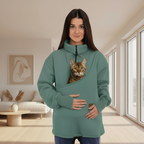 Woman wearing a green sweatshirt with cat in the pouch in a living room 