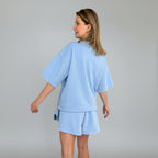Woman wearing a light blue outfit against a gray background