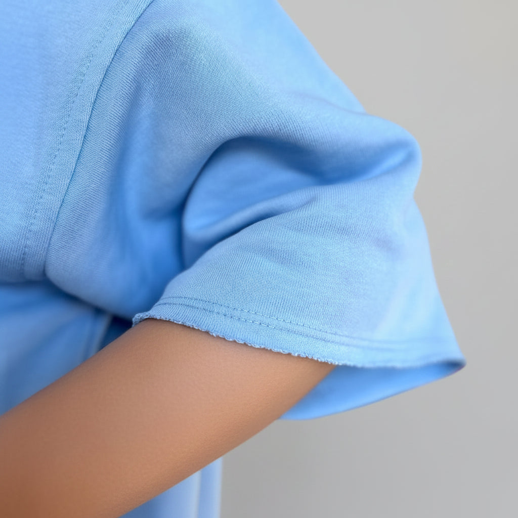 Close-up of a person wearing a light blue shirt with a neutral background