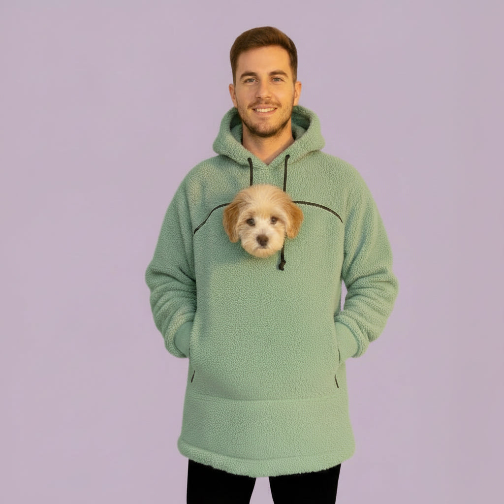 Person wearing a light  green hoodie with a dog peeking out of the front pocket against a purple background
