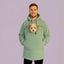 Person wearing a light  green hoodie with a dog peeking out of the front pocket against a purple background