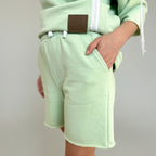 Light green hoodie and shorts set with a brand logo on a plain background
