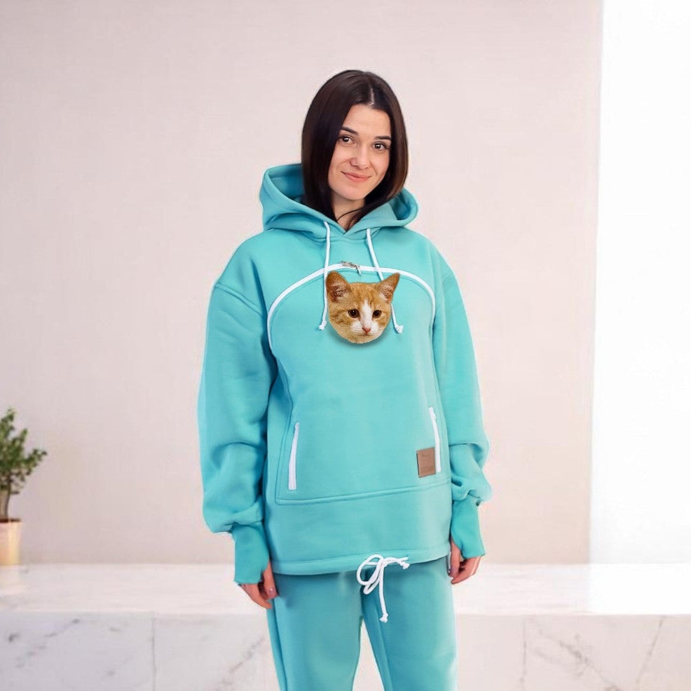 Person wearing a turquoise hoodie and pants set with a cat face design in a room. Main image
