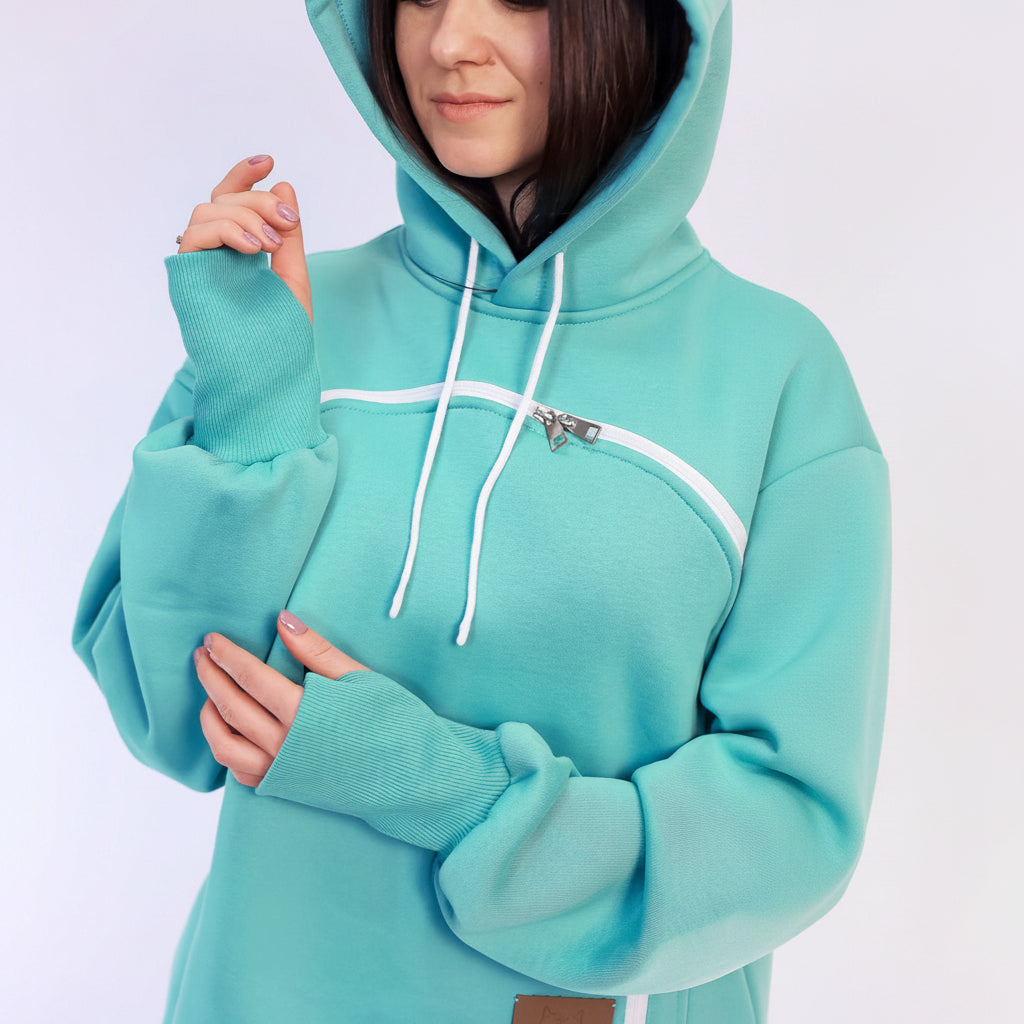 Person wearing a turquoise hoodie with white drawstrings on a light blue background