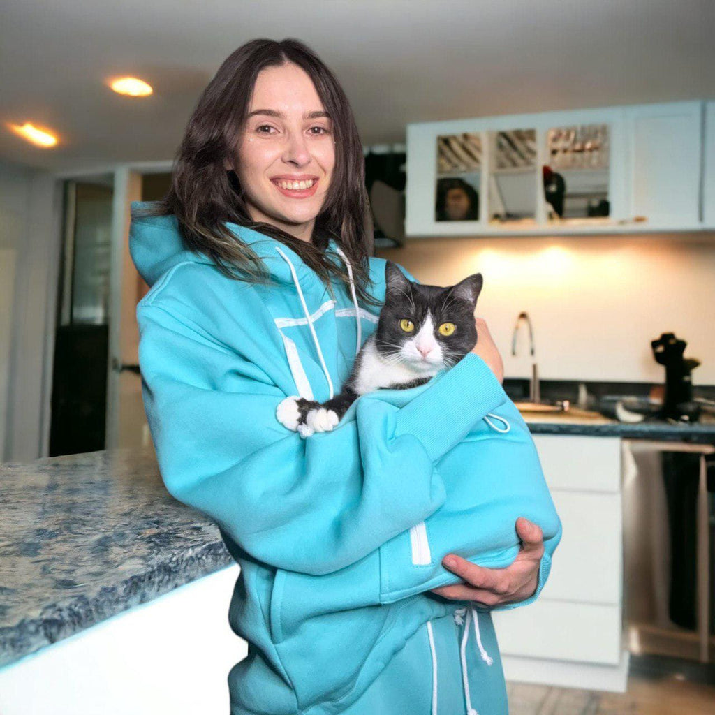 Person wearing a Mint Green hoodie holding a cat in a kitchen