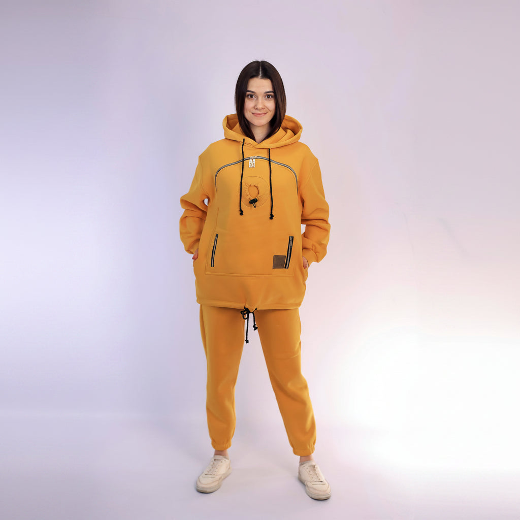 Person wearing a mustard hoodie and jogger set on a white background