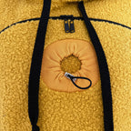 Close-up of a orange fleece hoodie with black drawstrings and a circular orange patch.