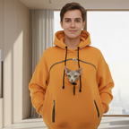 Men wearing an orange hoodie with a cat peeking out of the hood in a modern living room.