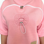 Close-up of a pink garment with white zippers and drawstrings on a white background