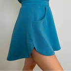 Teal shorts worn by a person on a plain background