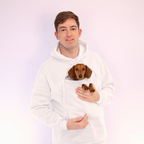 Person wearing a white hoodie with small dog inside on a light pink background