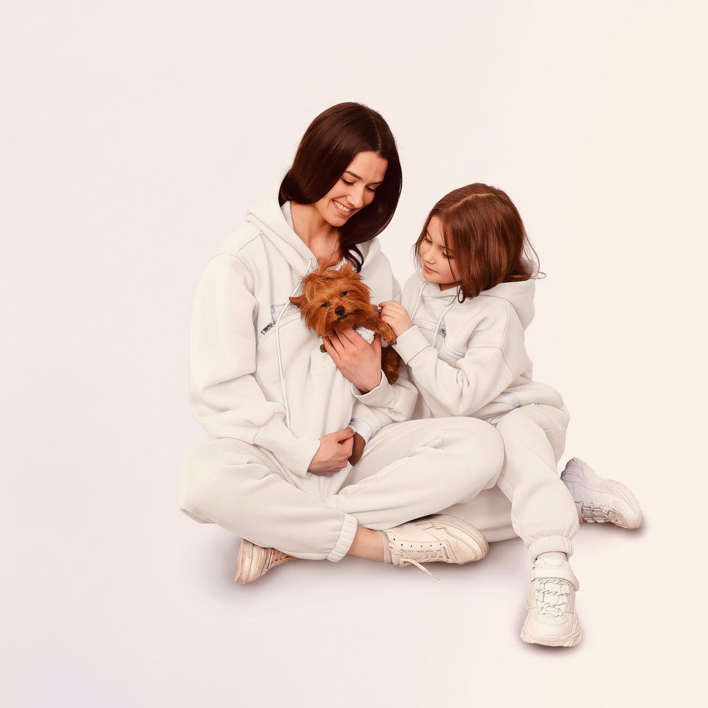 Two people in matching outfits sitting on the floor with a small dog. Main image