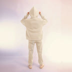 Person wearing a white hoodie and pants set on a light pink background