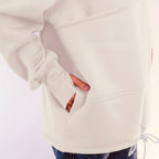 Person wearing a white sweatshirt with a plain background