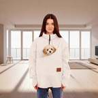 Women wearing a white fleece sweatshirt with a dog in the pouch in a living room 
