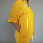 Person wearing a yellow outfit with a white zipper detail in an indoor setting